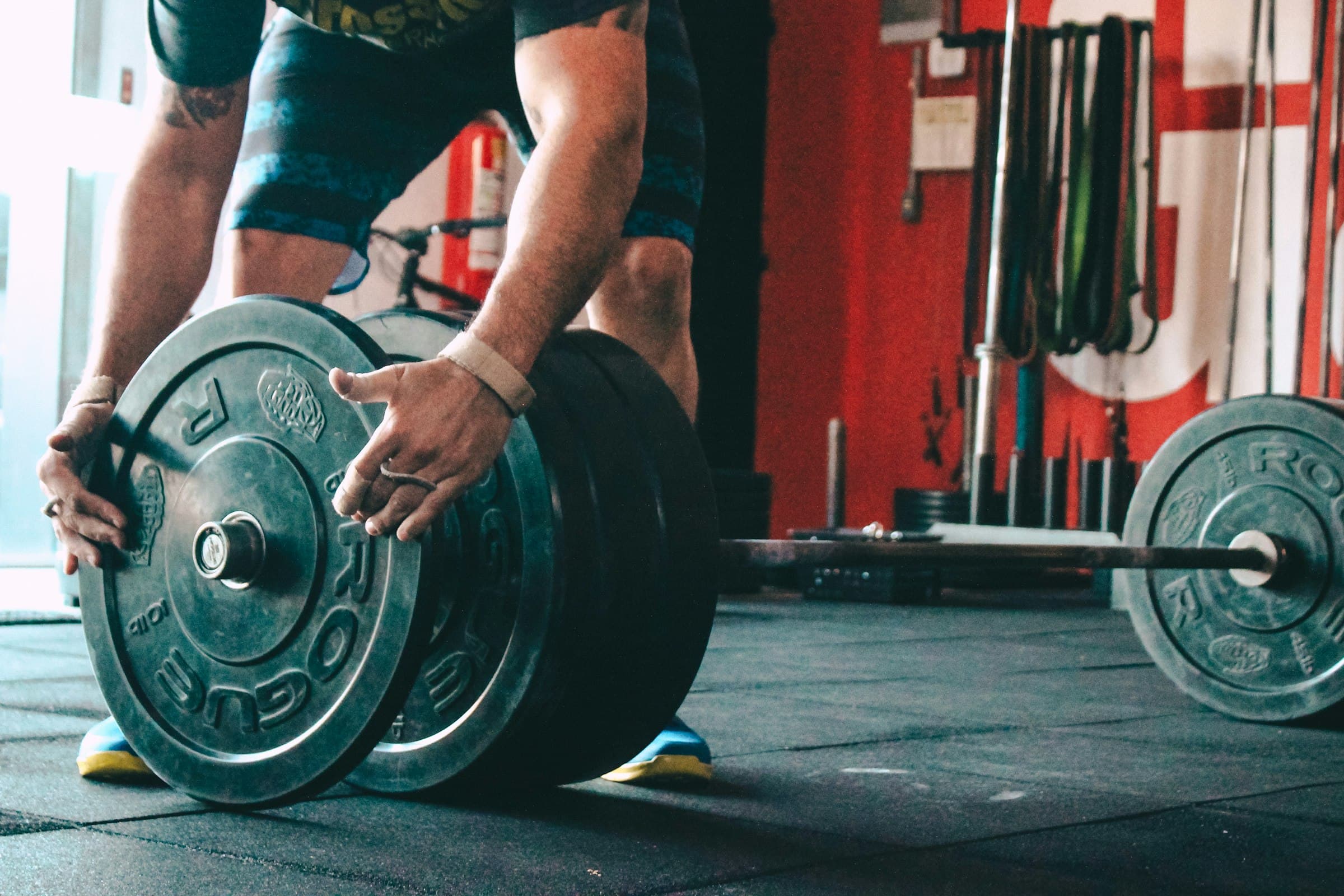 Hands loading a weight plate onto a barbell