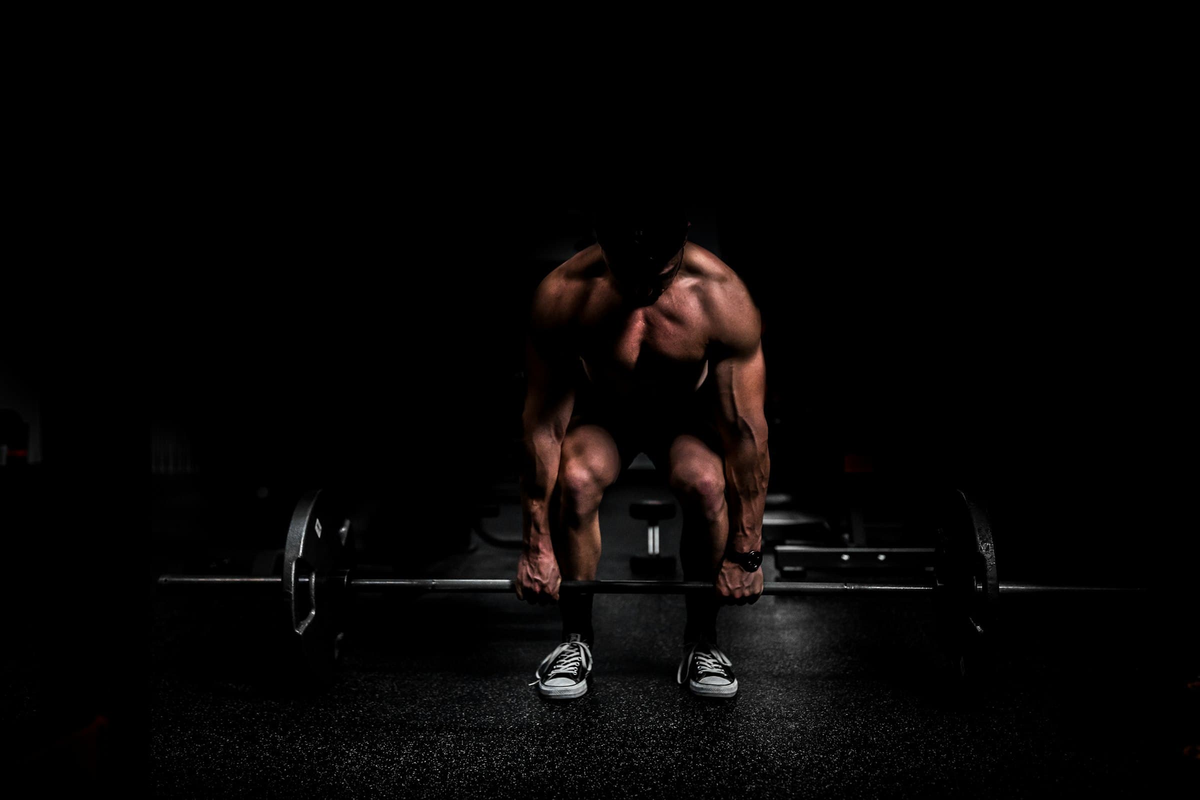 A lifter setting up for a deadlift in a dark gym