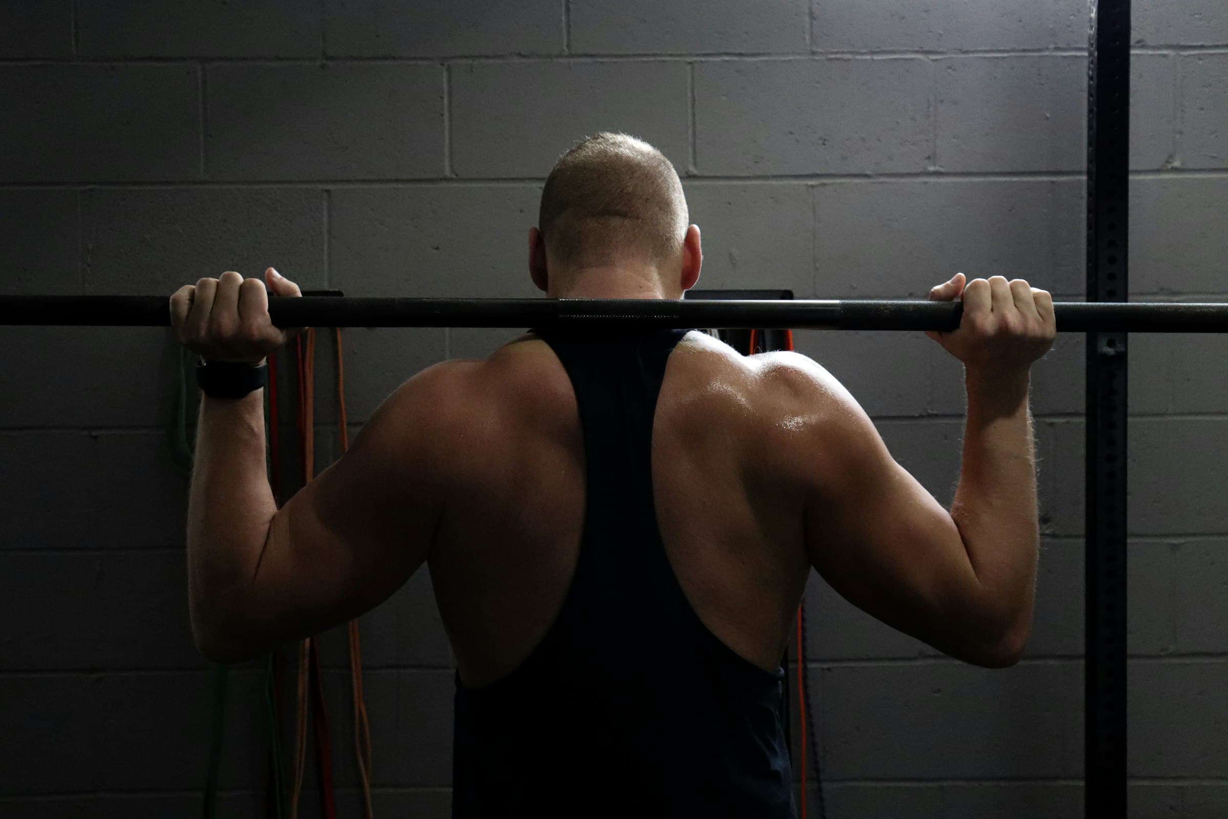 A man with a barbell across his upper back, ready to squat
